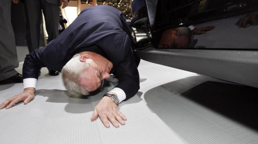 El presidente de Volkswagen AG, Martin Winterkorn, mientras se agacha para (supuestamente) ver los bajos de un Porche. En realidad, se está partiendo la caja. /EFE